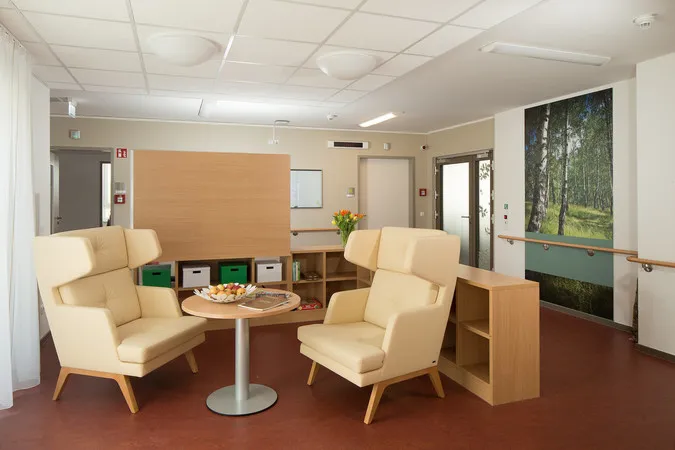 Helle Sitzecke mit zwei Sesseln, kleinem Tisch und großem Wald-Fotodruck an der Wand