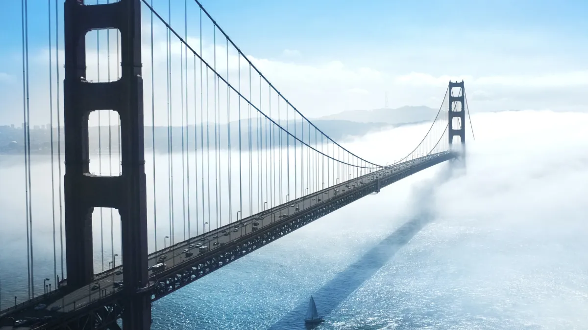 Golden-Gate-Brücke im Nebel über dem Meer, mit langem Schatten.
